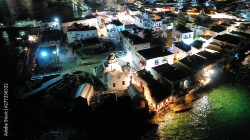 Aerial drone night shot of iconic and picturesque illuminated Little Venice in main town of Mykonos island nect to famous chapel of Paraportiani, Cyclades, Greece