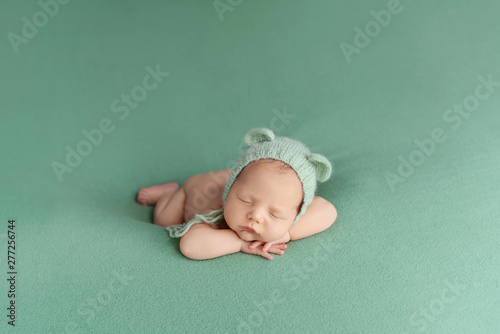 Sleeping newborn baby on a green background. Photoshoot for the newborn. A few days from birth.