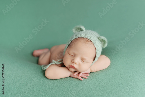 Sleeping newborn baby on a green background. Photoshoot for the newborn. A few days from birth.