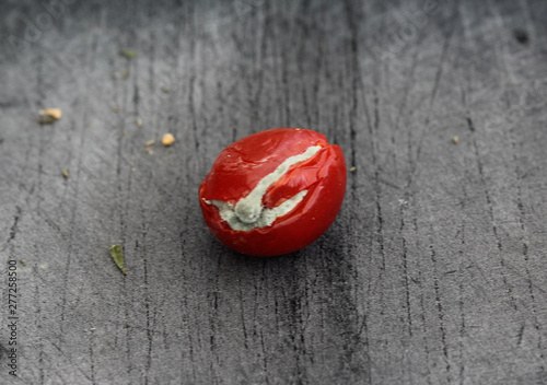 Rotten cherry tomato on black cutting board background