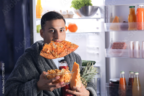 Εκτύπωση καμβά Afraid man caught in the act of choosing tasty food near refrigerator at night