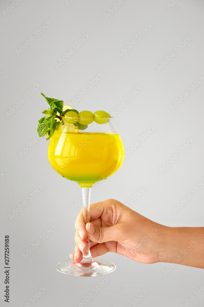 Female hand with glass of summer cocktail on light background - obrazy, fototapety, plakaty 