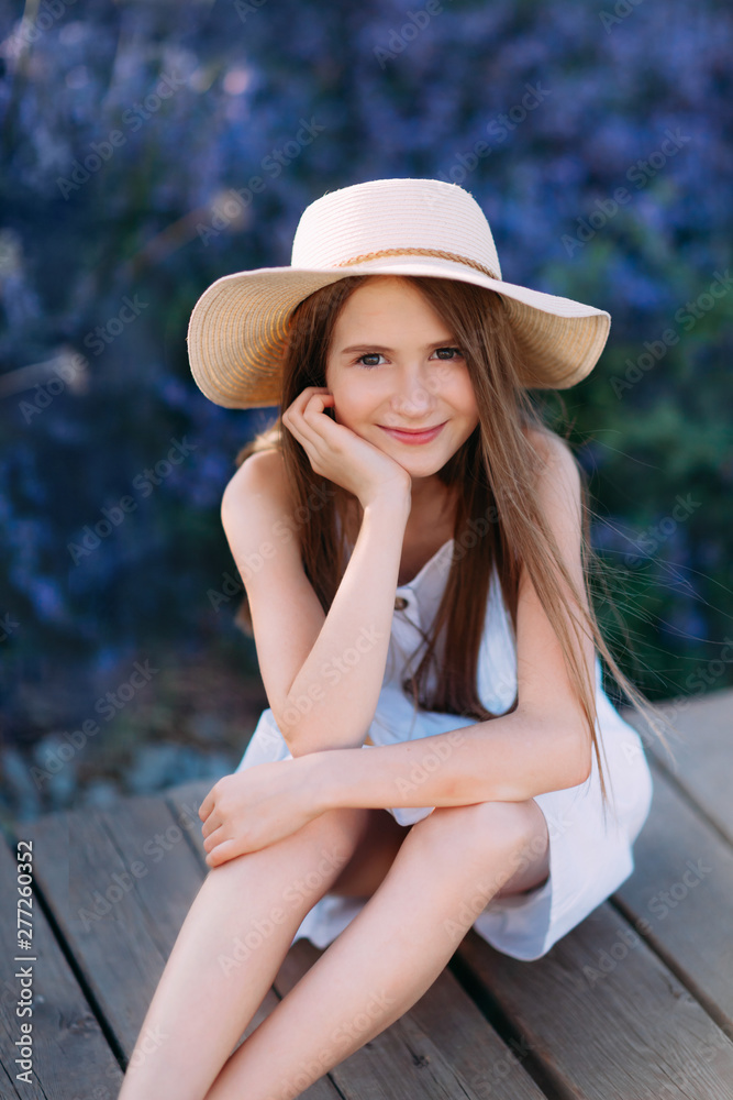 Portrait of smiling little girl, in white dress and hat