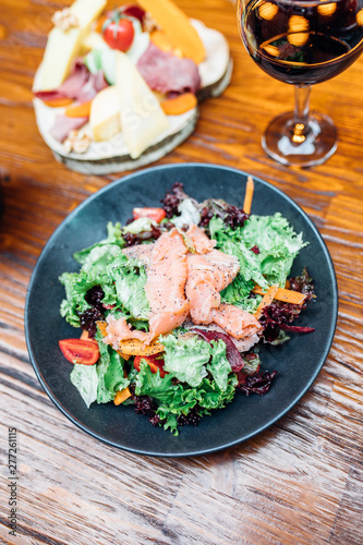 Dinner in the restaurant with Smoked salmon salad and appetizers on wooden dining table. This is Lunch or Dinner Restaurant or Cafe Concept Image.