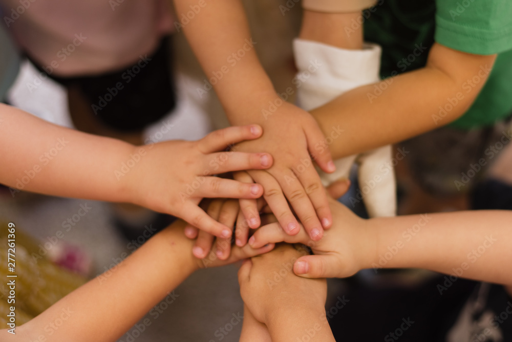 Children's hands piled on top of each other. Children's team and team building among the little guys