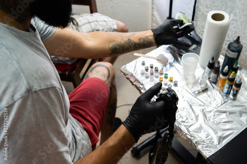 Professional tattoo artist preparing machine colors mix for artwork at studio saloon tattooing