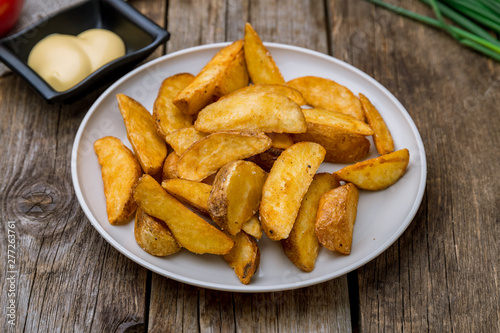 The potatoes wedges on the Board with cheese sause