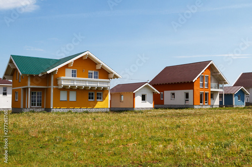 modern small colored houses built in the countryside against a blue sky with clouds.