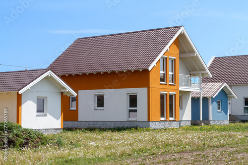 a small orange house with white windows and a dark brown metal roof.