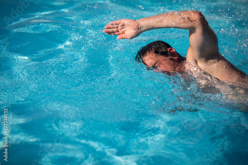 Male swimmer swimming crawl in an outdoor pool - keeping fit