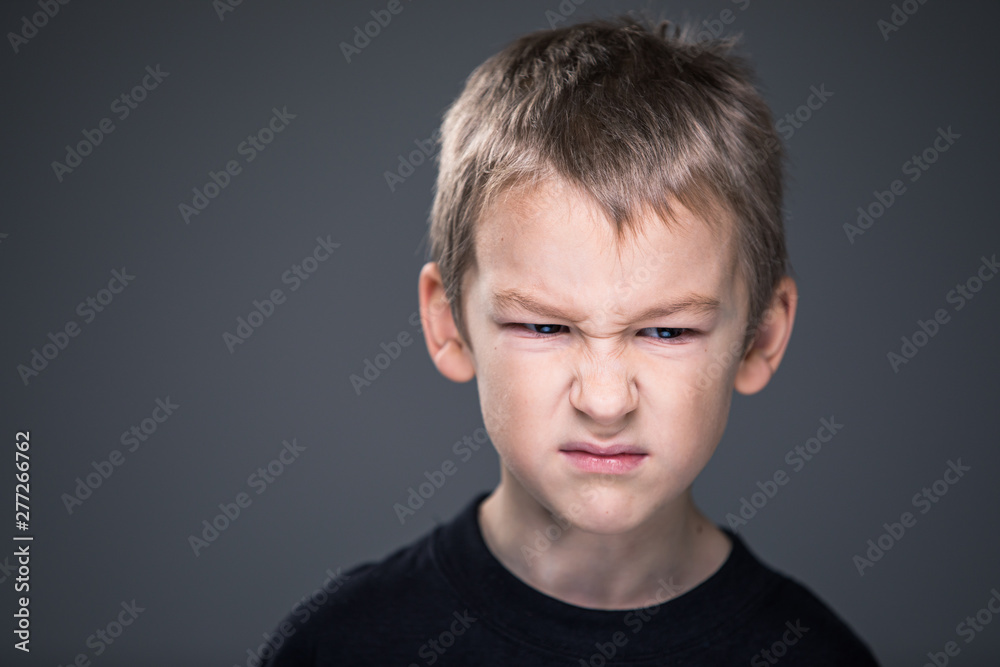 Loads of aggression in a little boy - education concept hinting behavioral problems in young children (shallow DOF) - little boy with hands clenched into fists about to punch someone