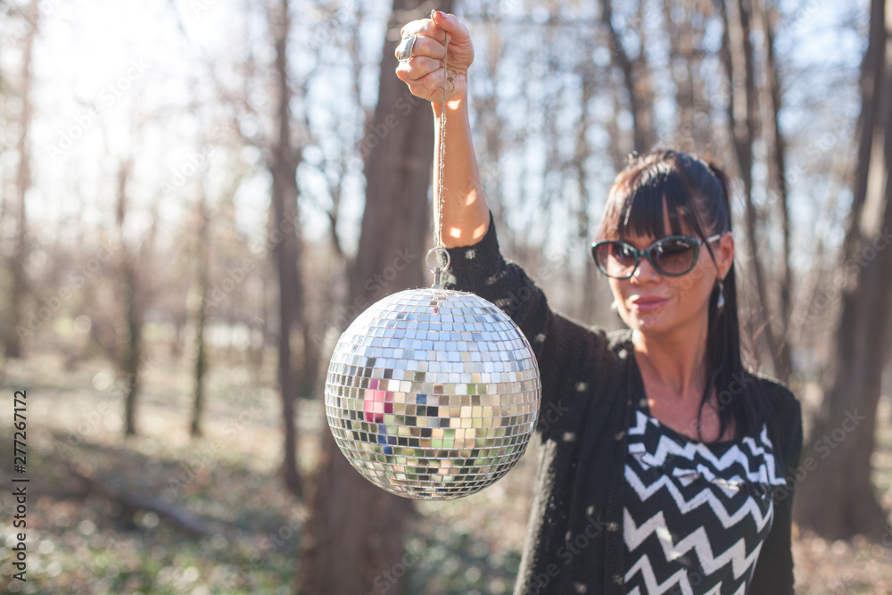 Naklejka premium young woman holding shining disco ball outdoors
