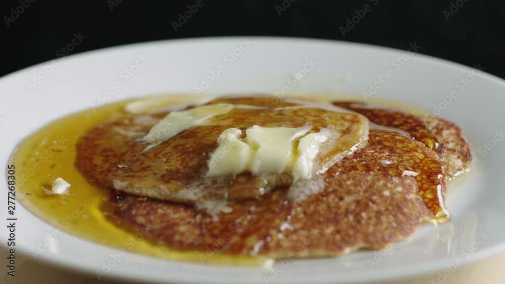 Plate of Butter-Topped Golden Pancakes Drizzled in Slow Motion with Maple Syrup