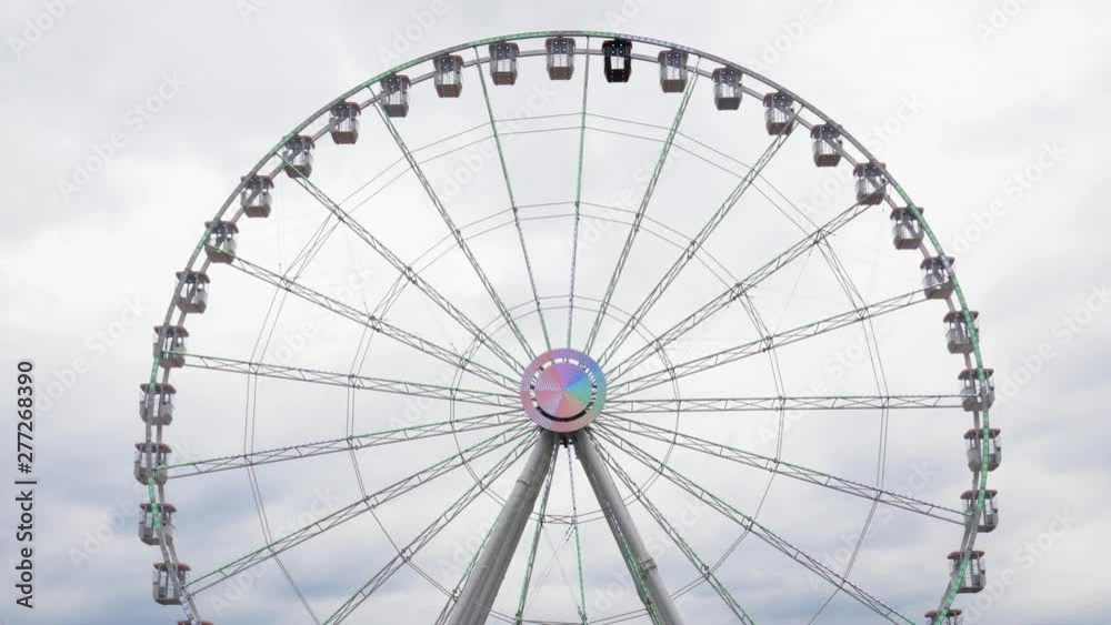 Big Ferris wheel spins against cloudy sky Big Ferris wheel spins against cloudy sky