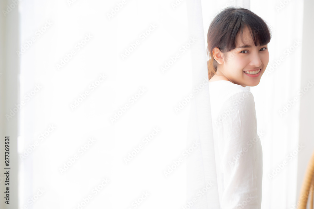 Portrait of beautiful young asian woman standing the window and smile while wake up with sunrise at morning, girl happy with freshness and cheerful, lifestyle and relax concept. Portrait of beautiful young asian woman standing the window and smile while wake up with sunrise at morning, girl happy with freshness and cheerful, lifestyle and relax concept.
