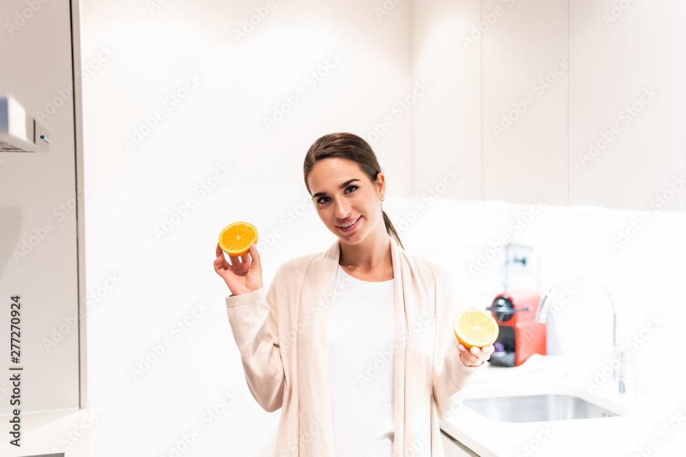 Funny and joyful young woman holding orange slices in the kitchen Funny and joyful young woman holding orange slices in the kitchen