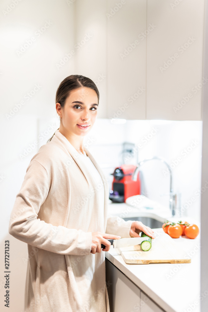 Young Woman Cooking in the kitchen. Young woman cut vegetables for salad. Young Woman Cooking in the kitchen. Young woman cut vegetables for salad.