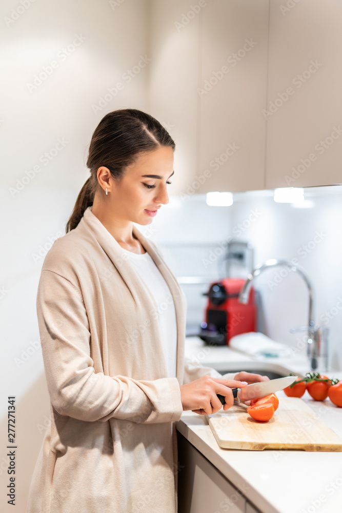 Young woman cooking in the kitchen healthy food, vegetable Salad. Holding a knife and cutting vegetables on a cutting board. Healthy lifestyle cooking at home. Young woman cooking in the kitchen healthy food, vegetable Salad. Holding a knife and cutting vegetables on a cutting board. Healthy lifestyle cooking at home.