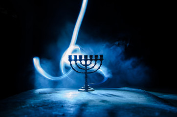 Low key image of jewish holiday Hanukkah background with menorah on dark toned foggy background