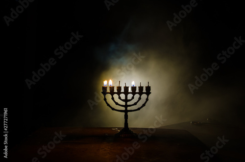 Low key image of jewish holiday Hanukkah background with menorah on dark toned foggy background photo