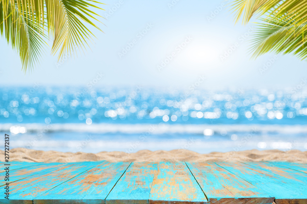 Top of wood table with seascape and palm leaves, blur bokeh light of calm  sea and