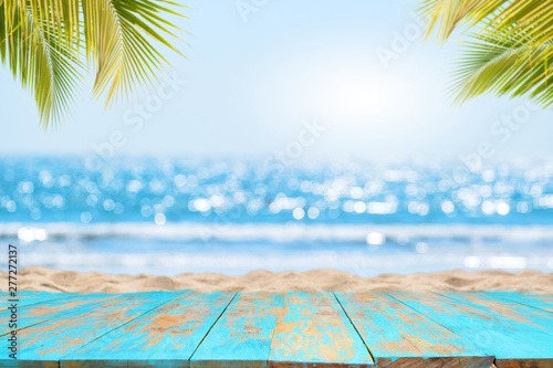 Fototapeta Naklejka Na Ścianę i Meble -  Top of wood table with seascape and palm leaves, blur bokeh light of calm sea and sky at tropical beach background. Empty ready for your product display montage.  summer vacation background concept.