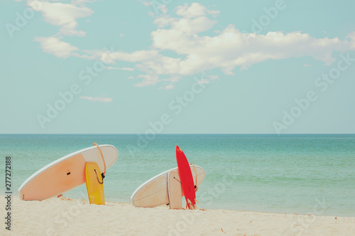 Surfboard on sand tropical beach with seascape calm sea and sky background. summer vacation background and water sport concept. retro color tone effect.