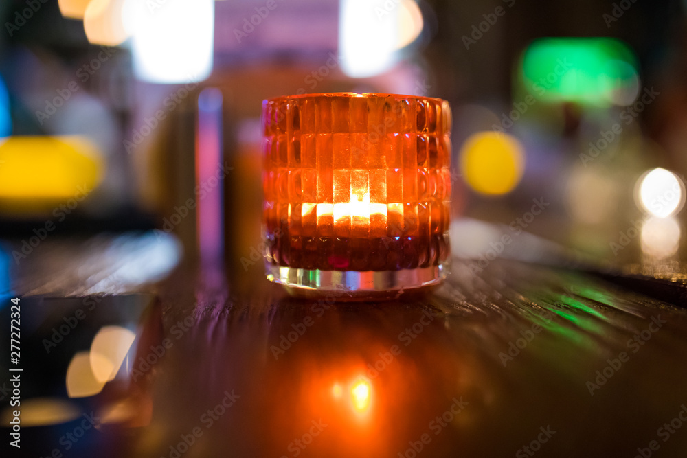 Decorative Orange or red candle light in glass on wooden table at night in cafe or restaurant background interior Decorative Orange or red candle light in glass on wooden table at night in cafe or restaurant background interior