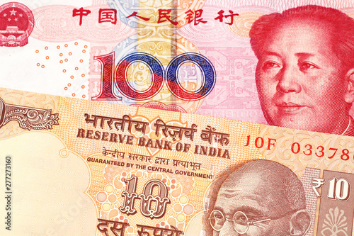 An orange  Indian ten rupee bill  close up with a red  one hundred yuan Chinese renminbi note