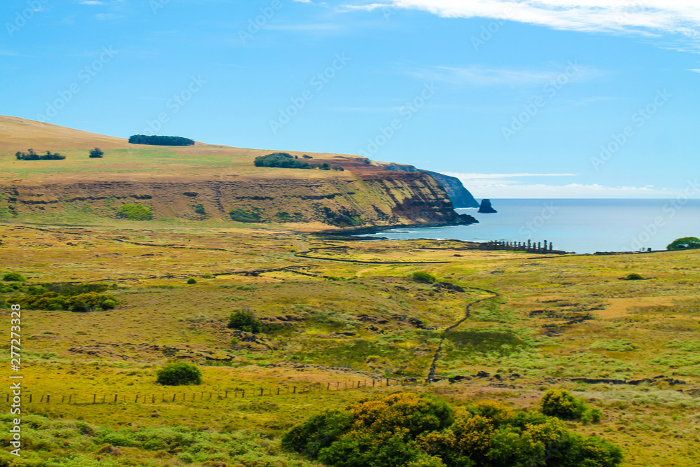 Fototapeta premium Coastal view of Easter Island, Chile, featuring the deep blue sea and towering mountains in the background. The island's rugged terrain and natural beauty make it a stunning destination