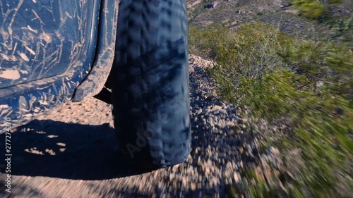 ATV Tire Low Angle on Edge. view moves down behind the front tire of an all terrain vehicle in the desert photo