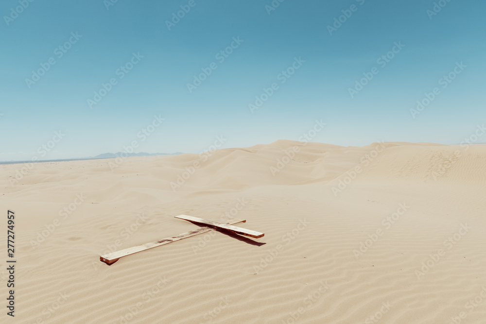Naklejka premium a wooden cross on a sand dunes with blue sky