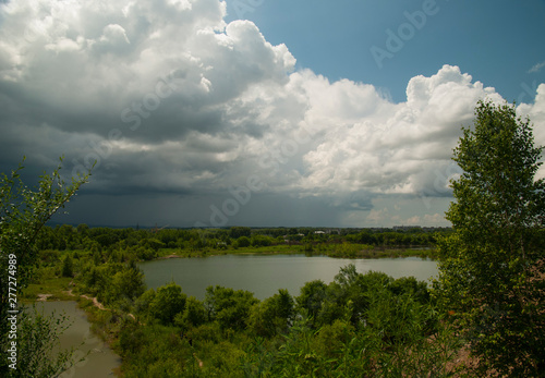 Large thunderstorm clouds, different coloured lakes and dark green vegetation.