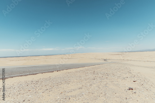 Fototapeta Naklejka Na Ścianę i Meble -  a road in the middle of the sand dunes in the desert.