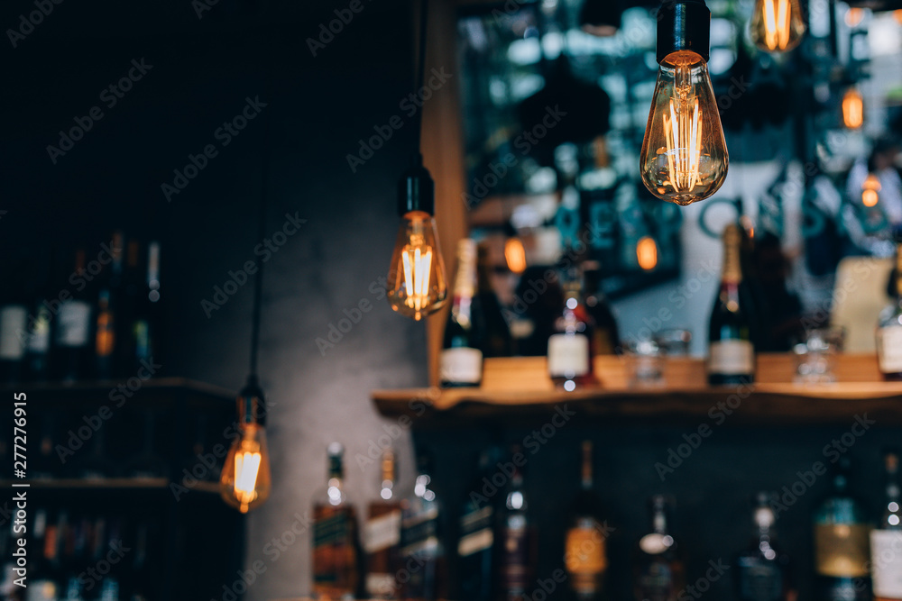 Vintage luxury interior lighting decor at Restaurant, cafe or bar. old Vintage light bulb lamps. Restaurant Bar or Cafe interior design. Vintage Light bulbs in front of alcoholic drinks bottles shelf