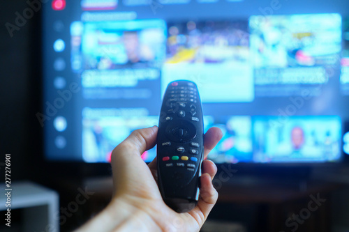 hand holding a tv remote, swithing media chanels screen photo