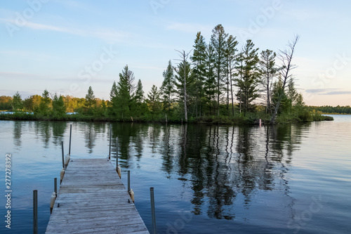 Pier jutting out into reflections of an island in the Chippewa Flowage near the shore of a Northwoods Forest park