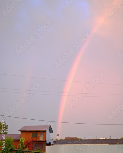 sector double high rainbow in the sky over the roofs of houses in evening