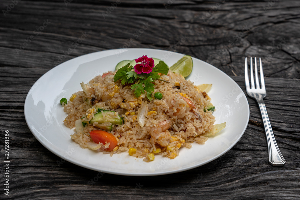 Fried rice with shrimps and vegetables in a white dish on an old wooden table, close up . Thai food , Thai cuisine Fried rice with shrimps and vegetables in a white dish on an old wooden table, close up . Thai food , Thai cuisine