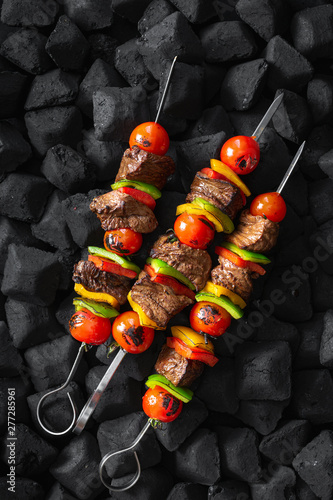 Fotografie Beef skewers being grilled on a embers top view