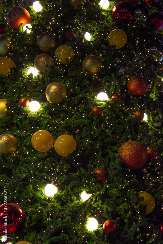 Illuminated decoration of Christmas tree with hanging golden yellow and red ball.