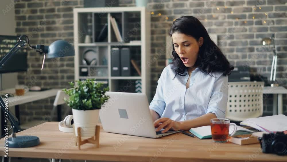 Tired office manager attractive girl is using laptop typing then yawning feeling unhappy and exhausted at work. Overwork, busy millennials and deadline concept. Tired office manager attractive girl is using laptop typing then yawning feeling unhappy and exhausted at work. Overwork, busy millennials and deadline concept.