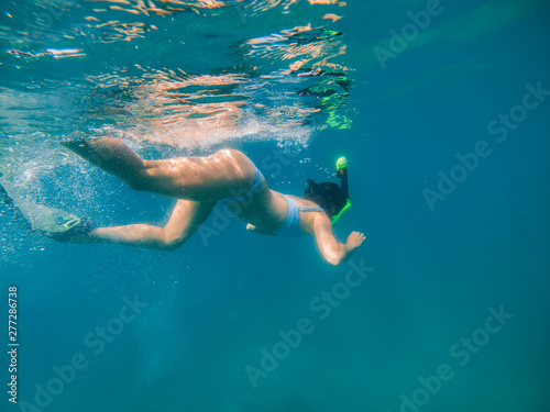 woman with snorkeling mask and flippers looking at sea bottom