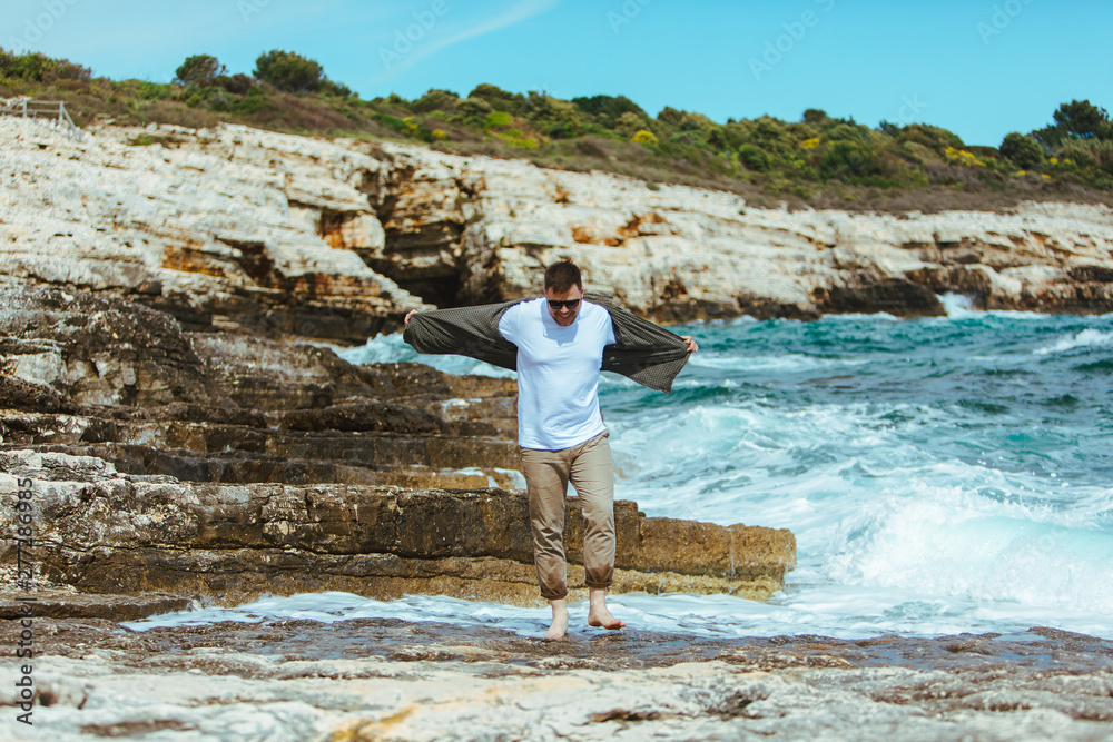 man walking by rocky beach in windy day summer vacation. enjoy sea view