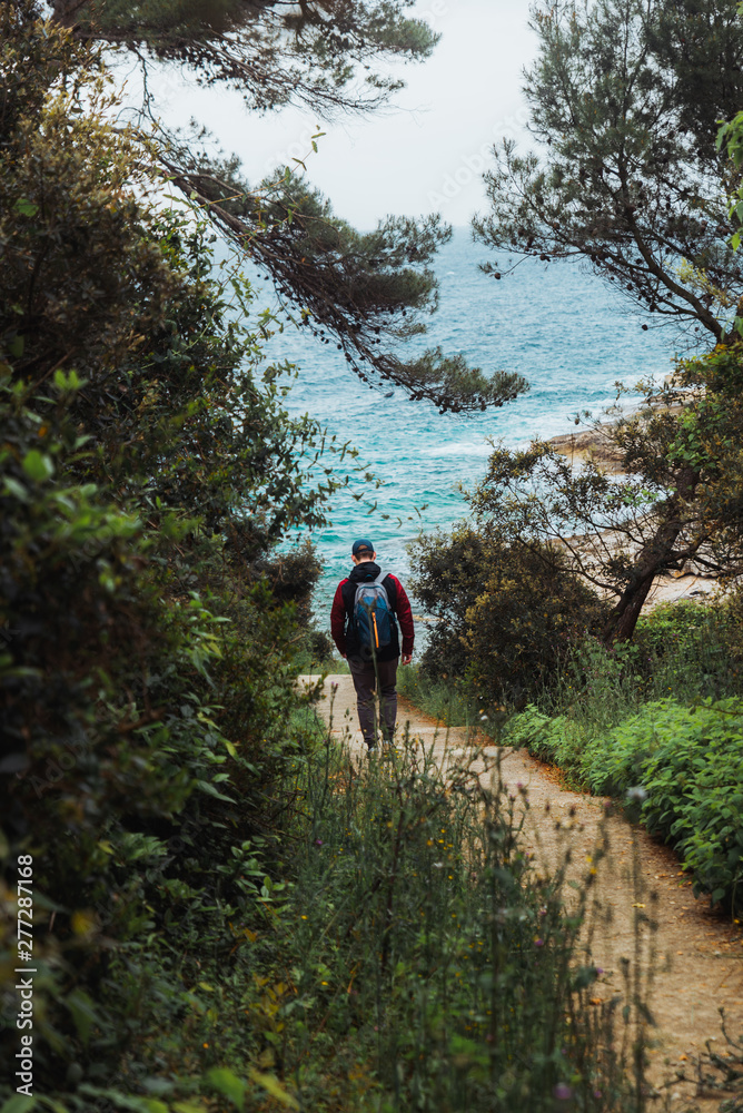 man walking by trial to sea beach overcast weather man walking by trial to sea beach overcast weather