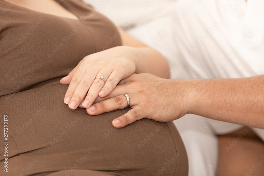 husband and wife take their hands and hold their stomachs while pregnant while giving birth husband and wife take their hands and hold their stomachs while pregnant while giving birth