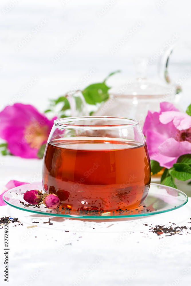 fragrant tea with wild rose in a glass cup on a white background, vertical - obrazy, fototapety, plakaty 