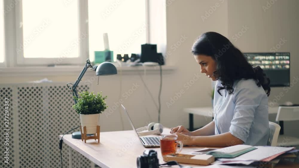 Attractive young businesswoman is using laptop getting good news clapping hands laughing in office. Successful people and modern technology concept. Attractive young businesswoman is using laptop getting good news clapping hands laughing in office. Successful people and modern technology concept.