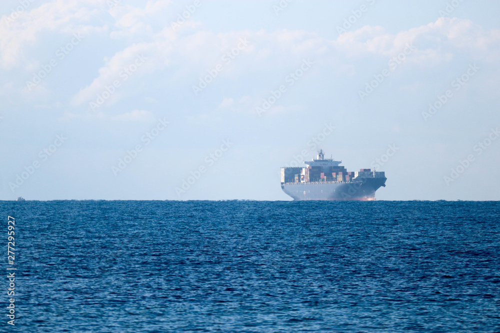 Distant view in haze of a large cargo container ship in the Mediterranean sea near Livorno, Italy