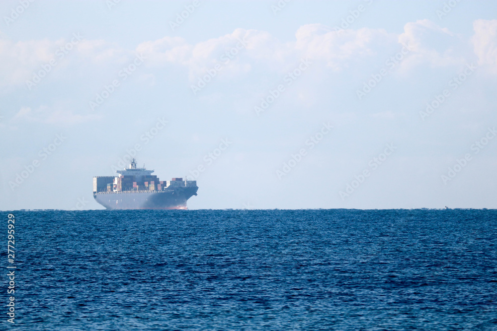 Distant view in haze of a large cargo container ship in the Mediterranean sea Distant view in haze of a large cargo container ship in the Mediterranean sea
